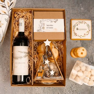 cadou in cutie de carton natur cu vin rosu, turta dulce personalizata, fursecuri cu portocale, bulgari de zapada, brad din lemn lacuit, culoare maro, cu cerb, conuri naturale, stelute de lemn albe