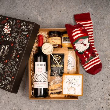 cutie cadou cu sticla de vin rosu, Faurar, crama Ceptura, borcan cu dulceata de ardei iuti, borcan mustar artizanal Gurmandia, saratele cu susan negru, branza maturata cu ierburi sasesti, turta dulce personalizabila full print, sosete de craciun, rosii cu dingi albe si un Mos Craciun care fumeaza pipa
