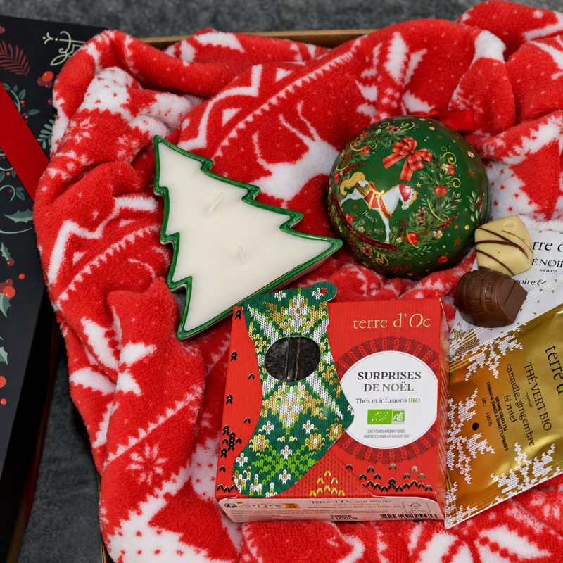 Coș cadou corporate de Crăciun cu pătură roșie și dulciuri, prezentat într-o cutie festivă.