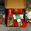 Pachet cadou corporate de Crăciun cu șosete festive roșii, dulciuri și lumânare.